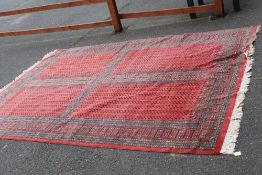 A LARGE EASTERN WOOLLEN RUG MAINLY RED AND BLACK - APPROX 330 x 224 cm