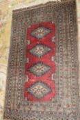 AN ANTIQUE RED EASTERN WOOLLEN RUG