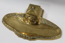 A 20TH CENTURY BRASS SECESSIONIST STYLE INKSTAND, with central inkwell having hinges lid, W 32 cm