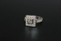 A HALLMARKED HANDMADE 18 CARAT WHITE GOLD DIAMOND RING, set with a central Princess cut diamond of