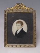 A 19TH CENTURY OVAL PORTRAIT MINIATURE OF A YOUNG MAN, in a black jacket and white stock,