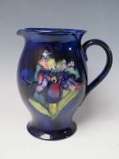 A MOORCROFT POTTERY IRIS PATTERN JUG, of baluster form, on a blue ground, signature and painted