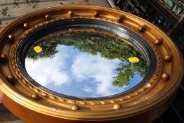 A GILT FRAMED PORTHOLE STYLE FRAMED MIRROR AND A DECO STYLE MIRROR