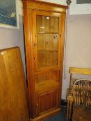 A MODERN GLAZED HONEY PINE CORNER CABINET
