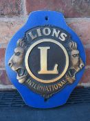 A LIONS INTERNATIONAL CLUB PLAQUE MOUNTED ON WOODEN BACK BOARD