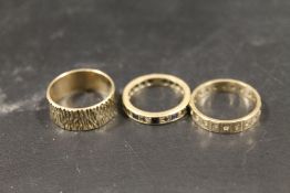 A HALLMARKED 9 CARAT GOLD BARK EFFECT BAND TOGETHER WITH TWO GEM SET ETERNITY RINGS APPROX 8.1G