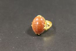 AN INDISTINCTLY MARKED YELLOW METAL OVAL CABOCHON GOLDSTONE RING - APPROX WEIGHT 6 G