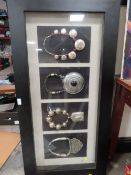 A LARGE FRAMED AND GLAZED DISPLAY OF FOUR UNUSUAL LARGE NECKLACES