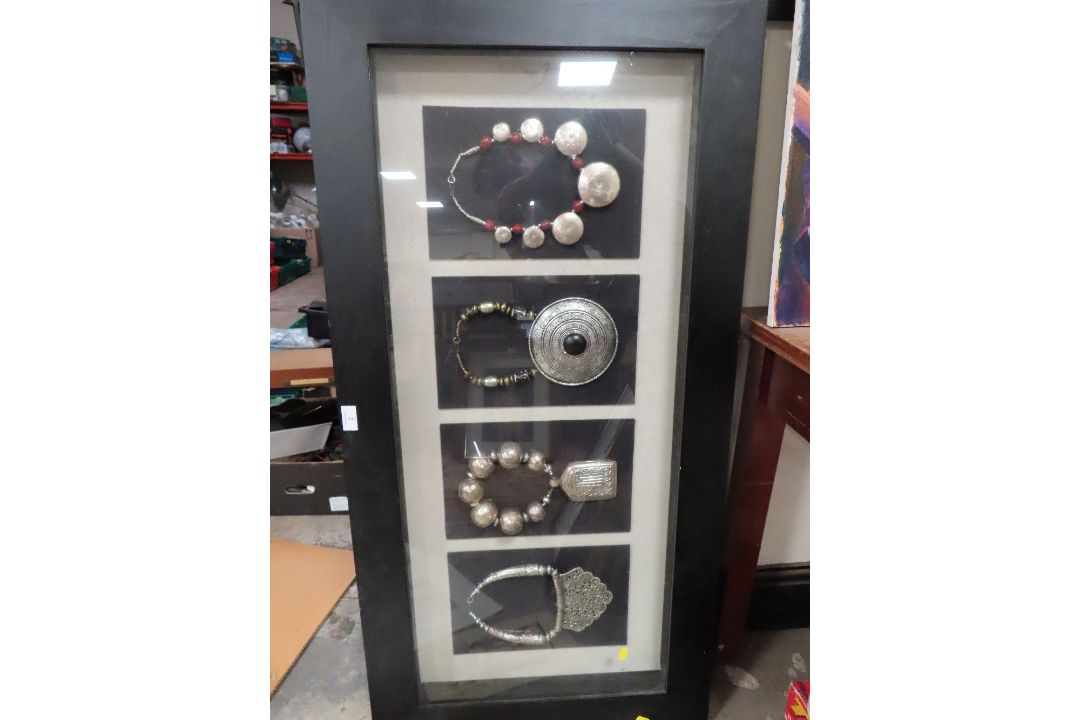 A LARGE FRAMED AND GLAZED DISPLAY OF FOUR UNUSUAL LARGE NECKLACES