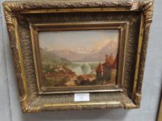A GILT FRAMED SMALL OIL ON CARD OF A MOUNTAINOUS LAKESIDE VILLAGE