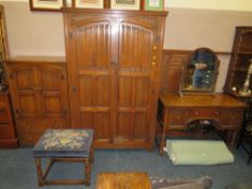 AN OAK LINENFOLD BEDROOM SUITE COMPRISING DOUBLE WARDROBE, TALLBOY, DRESSING TABLE, MIRROR, STOOL