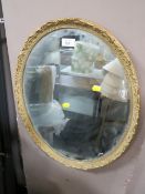 A VINTAGE OVAL GILT FRAMED MIRROR