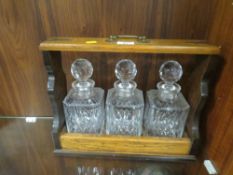 A VINTAGE BRASS MOUNTED OAK THREE BOTTLE TANTALUS