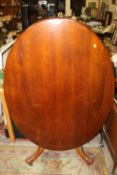 A MAHOGANY TILT TOP OVAL TABLE ON CARVED BASE