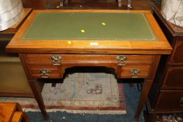 AN EDWARDIAN MAHOGANY LEATHER TOPPED FOLD OVER DESK / GAMES TABLE WITH THREE DRAWERS W-86 CM