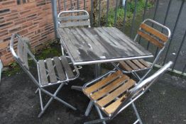AN ALUMINIUM / HARDWOOD CAFE STYLE PATIO / GARDEN TABLE SET WITH FOUR FOLDING CHAIRS