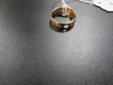 A HALLMARKED 18 CARAT GOLD BAND SET WITH THREE RUBY TYPE STONES - CENTRAL STONE IS DETACHED approx