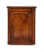 A REGENCY ELM AND BURR ELM CORNER CUPBOARD, CIRCA 1820