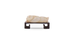 A Chinese pale celadon jade carving of a reclining boy