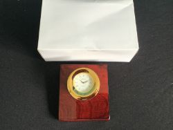 A DESK CLOCK ON A WOODEN POLISHED BASE
