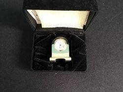 A MINIATURE STAINLESS STEEL CLOCK IN CASE