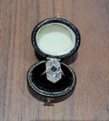 An Art Deco yellow metal ring, the large floral setting set with a central princess cut sapphire,
