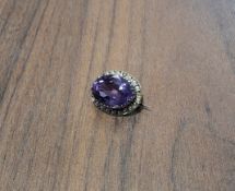 A Victorian yellow metal mounted halo brooch set with a central oval amethyst, surrounded by seed