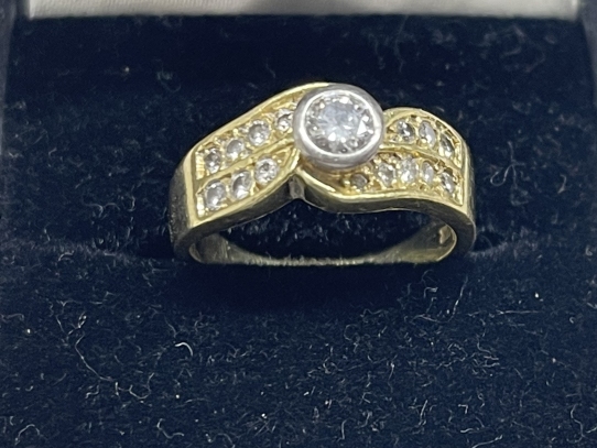 Jewellery: Yellow metal ring seventeen stone crossover, centre rub over set with a single