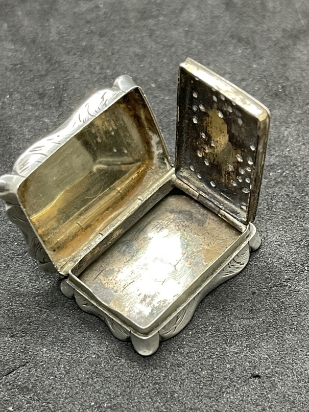 Early 19th cent. White metal vinaigrette, shaped edge, engraved decoration to the front and back,