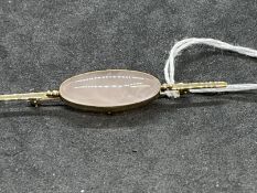 Jewellery: Yellow metal brooch set with an oval cabouchon cut rose quartz, 30mm x 12mm tests as