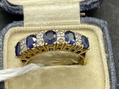 Jewellery: Yellow metal thirteen stone half hoop consisting of five oval cut sapphires, estimated
