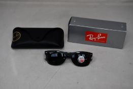 A pair of boxed Ray Ban New Wayfarer black on transparent green sunglasses.