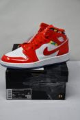 A pair of Nike Air Jordan 1 mid SE (GS) Chile Red/White Pollen (UK 5.5) (Damage to outer box).