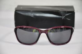 A pair of women's boxed Oakley She's Unstoppable 0OO9297 translucent Indigo black Iridium sunglasses