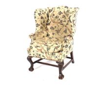A mahogany wing back chair in the George III manner, raised on carved cabriole supports
