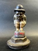 A car mascot depicting a crouching figure wearing a bowler hat, radiator cap mounted, approx. 5 1/2
