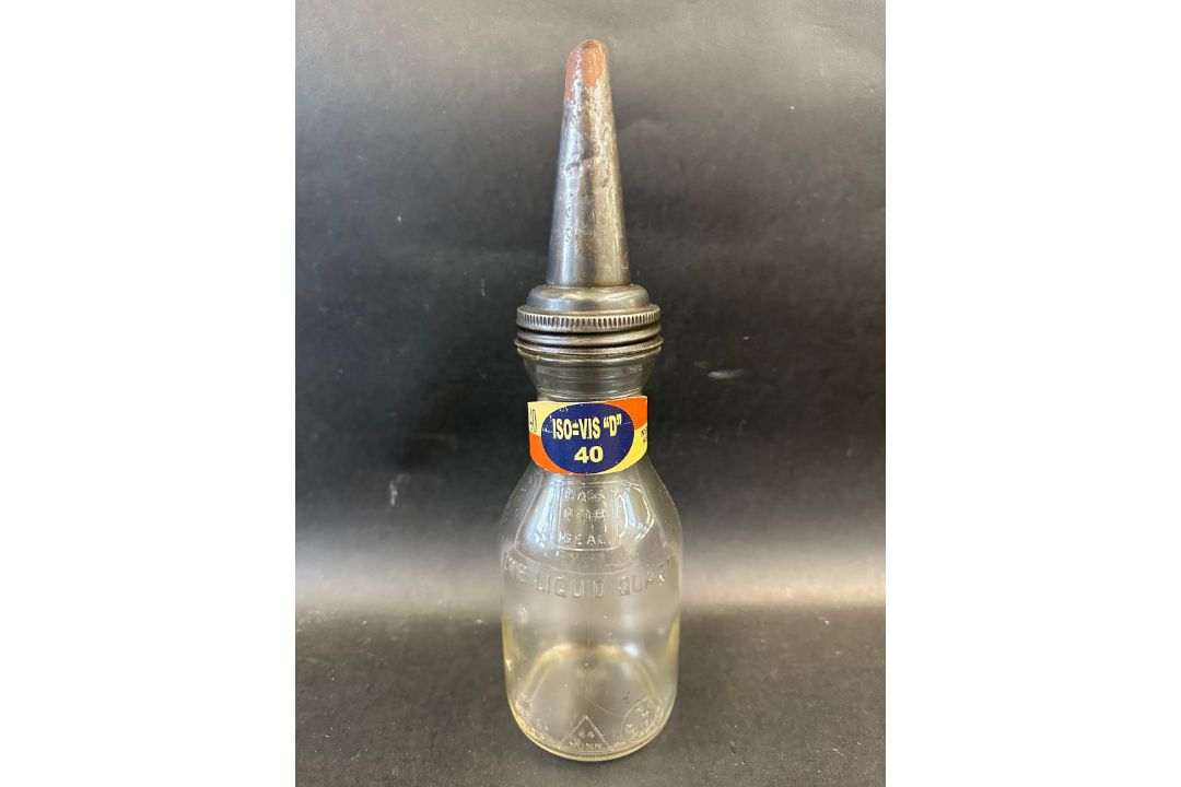 An American glass quart oil bottle with grade band on the neck and tin spout. - Image 1 of 2