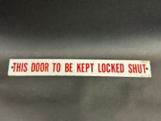 A small enamel sign bearing the words 'This door to be kept locked shut', 11 1/2 x 1 1/2