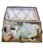 Small green chest containing various small dolls outfits and garments.