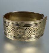 A Middle Eastern yellow metal engraved cuff style hinged bangle with traces of black enamel, a/f.