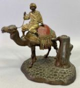 COLD PAINTED CAST METAL TABLE LIGHTER MODELLED AS A CAMEL & DRIVER standing by a tree trunk, 16cms
