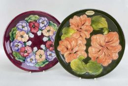 TWO MOORCROFT CABINET PLATES, comprising a Barbara Mountford pansy plate and a hibiscus example,
