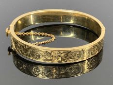 9CT ROSE GOLD HINGED HOLLOW BANGLE - engraved foliate decoration to one half, band width 10mm,