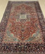 GOOD ANTIQUE PERSIAN RUG, probably Kashan, central navy blue medallion, on a madder scrolling vine