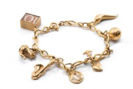 YELLOW METAL CHARM BRACELET, with various charms including 9ct gold, 18cms long, 13.9gms Provenance: