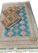 EASTERN WOOLEN RUG & TWO CUSHIONS, the rug being turquoise ground with repeating panel central block