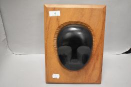 A heavy wooden plinth having ebonised tribal face carving.