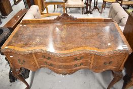 An early 20th century small sideboard or dressing table base having burr Walnut veneer and carved