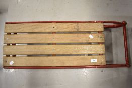 A vintage toboggan sledge having metal frame and wood seat