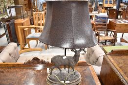 A modern table lamp having a resin cast deer figure and leather shade